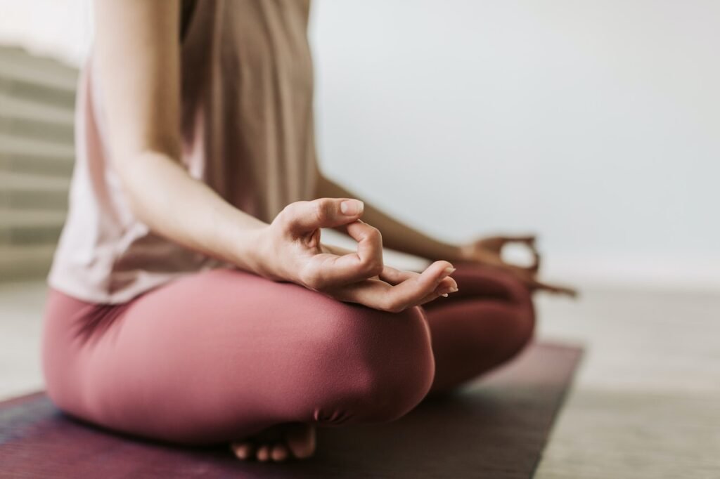 A woman meditating with closed eyes and her hands resting on her knees.